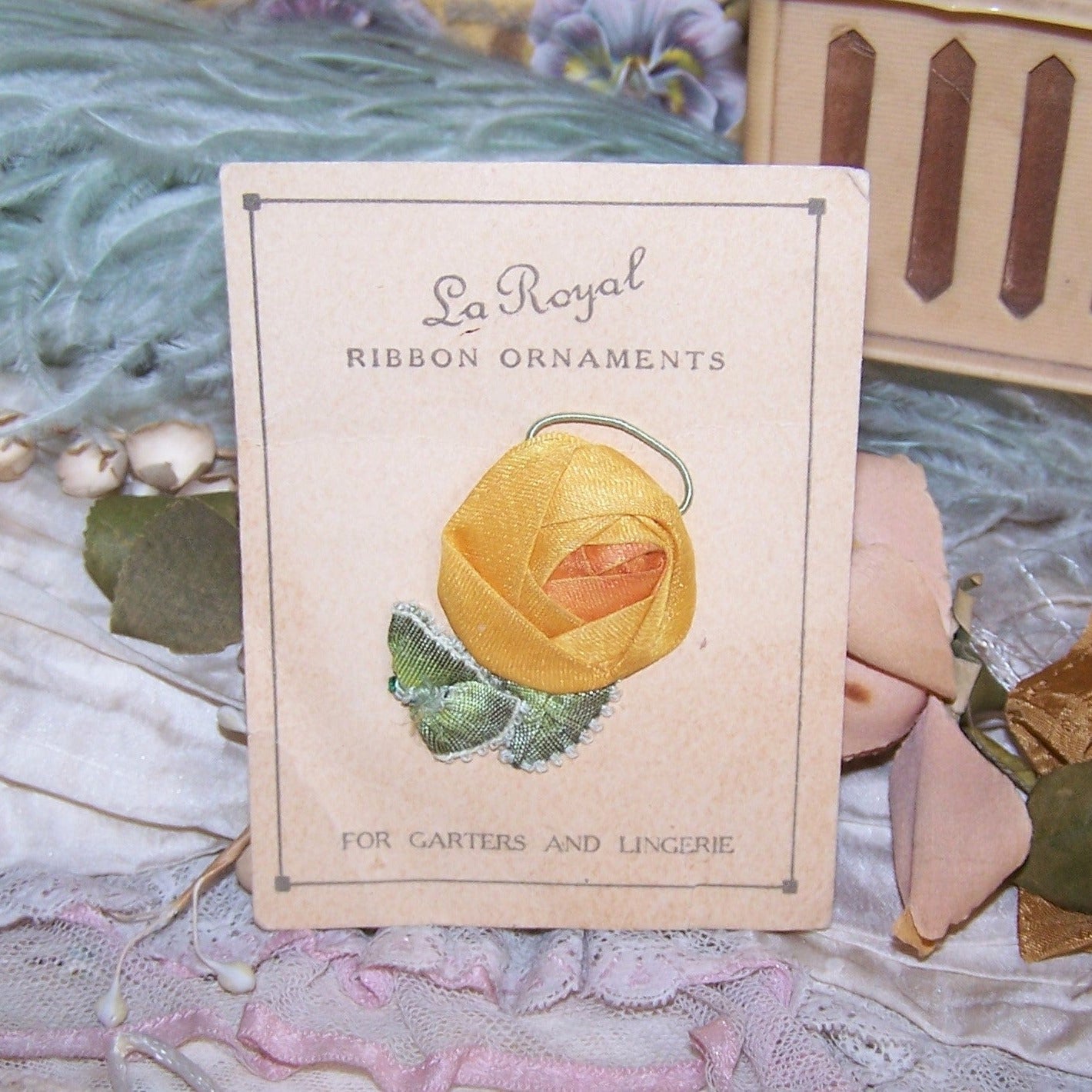 Art Deco La Royal Ribbon Ornament on Original Card - a mustard yellow flower with ruffled edge green leaves. Very nice ribbonwork with a patina of age.