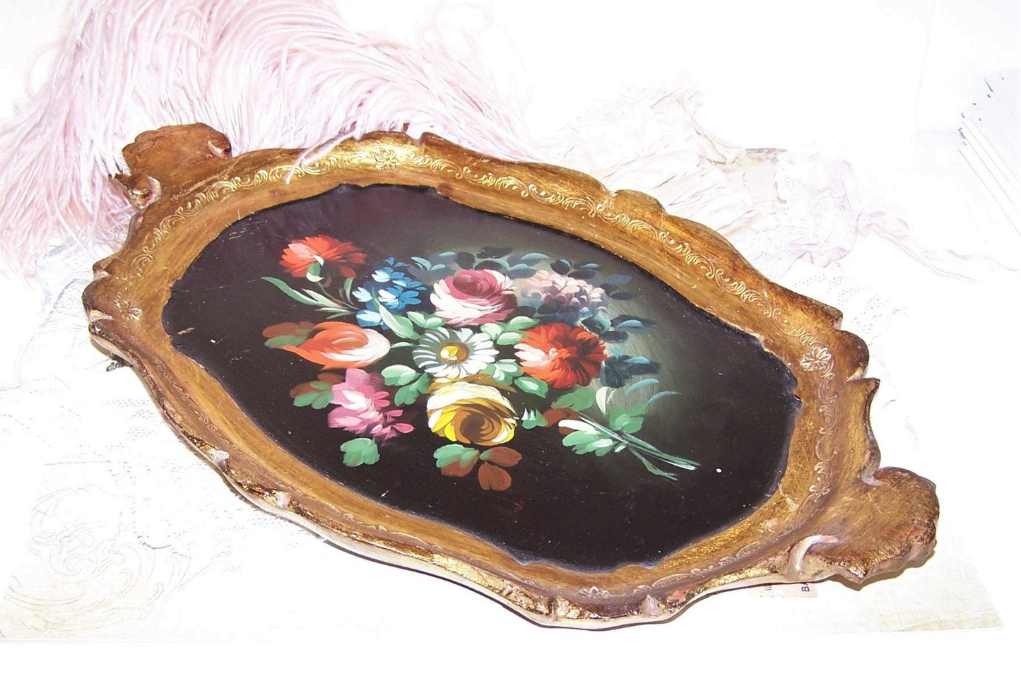 Italian-made, handpainted (in oils) wood tole tray. Gold with painted florals on a black background. Length of the tray is 14" x 9" wide. Lightweight piece.