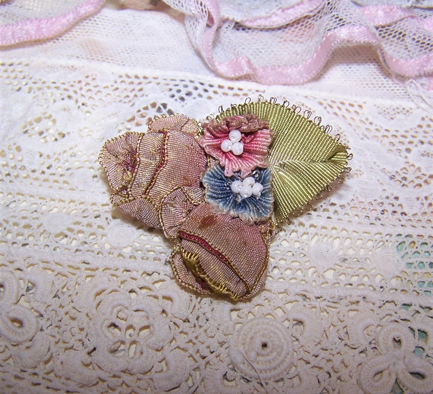 Art Deco French Ribbonwork applique. Design is of 2 maroon coiled roses with accent florals of blue and red ombre cotton. Seed bead centers.  1-3/4" x 1-1/2".