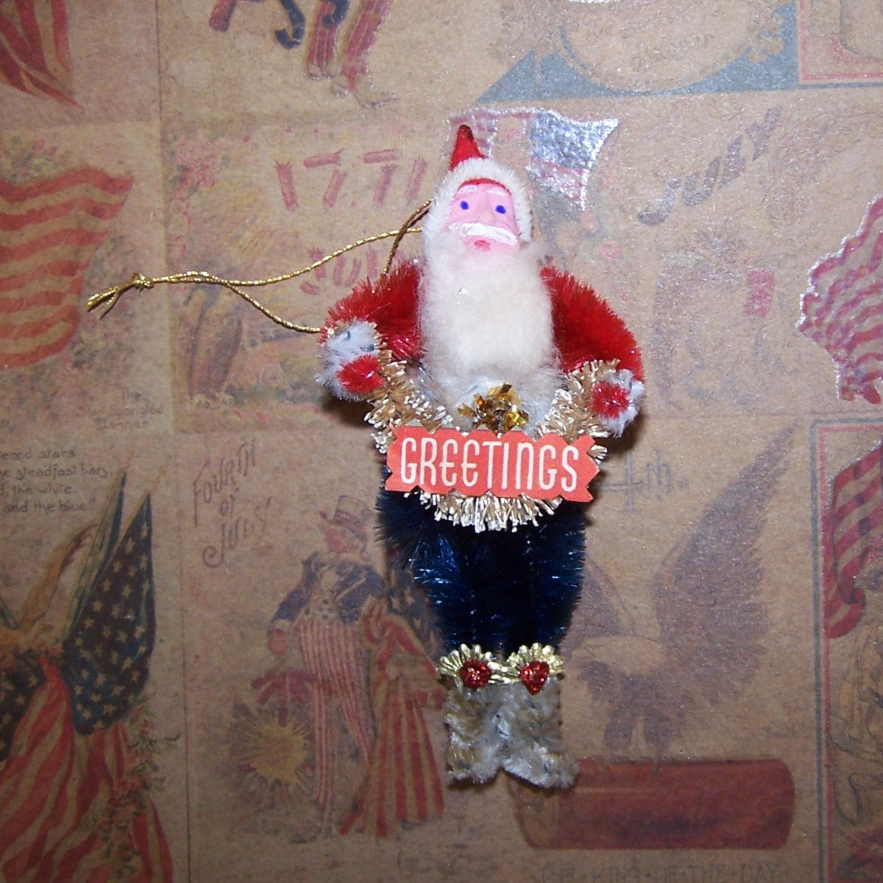 Vintage-style Santa Claus ornament with 'GREETINGS' sign on a decorative background