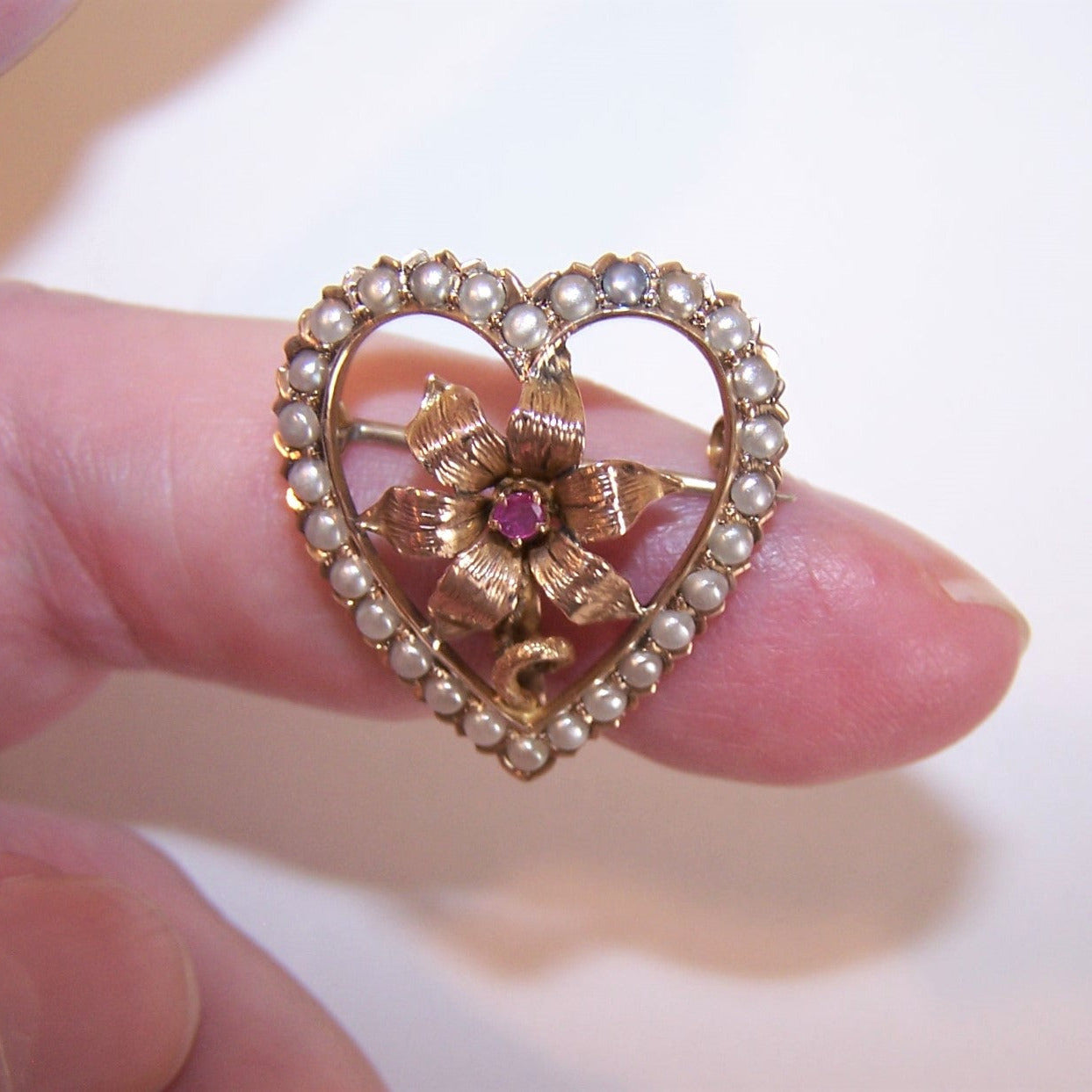 14K Yellow Gold brooch, watch pin or pendant. Heart shaped with a center flower set with a red ruby; the border has natural pearls. 1-1/16" x 1". 3.7 grams