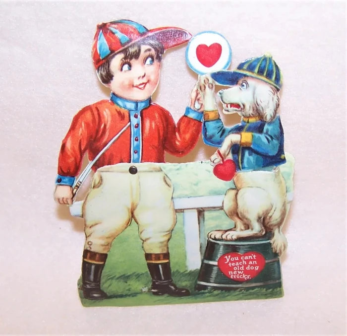 Here's an Art Deco mechanical high gloss Valentines Day card. The image is of a young boy dressed as a horse racing jockey holding up a heart sign to his dog (also dressed in horse racing garb). The hand of the boy and the paw of the dog move back and forth meeting in a HIGH FIVE sign.