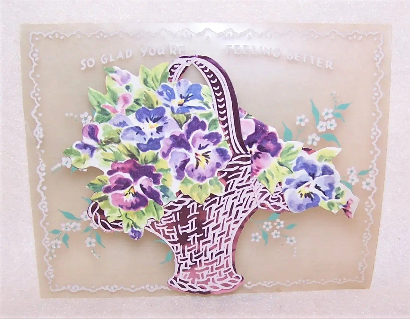 Colorful greeting card in 3 parts-Celluloid base with silk screened flowers, Pink aluminum foil basket and a Bouquet of pansies. So Glad You're Feeling Better.