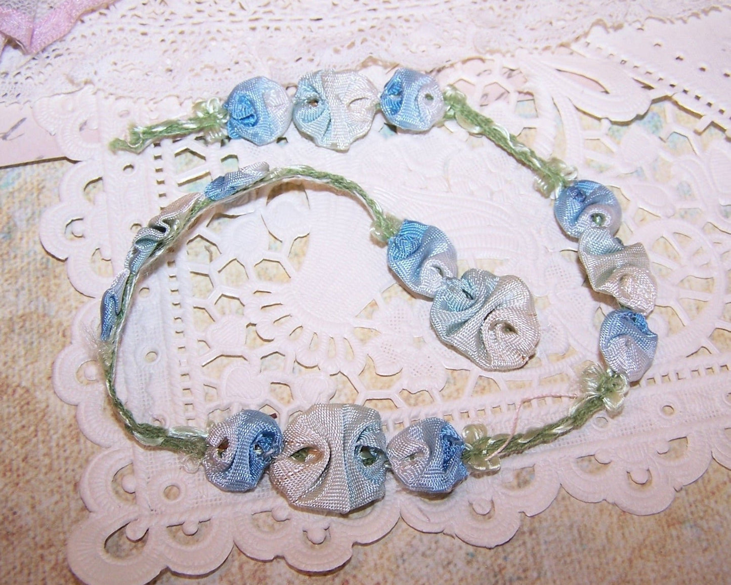 May I offer this bit of antique ribbon trim from France. Made of pale blue and white ombre ribbon, there is only 10" of the trim - this includes the 4 full sprays but does not include the end piece with only 2 buds - this is an extra 1-1/8" long. Width at the center is a bit over 1/2". An unusual design.