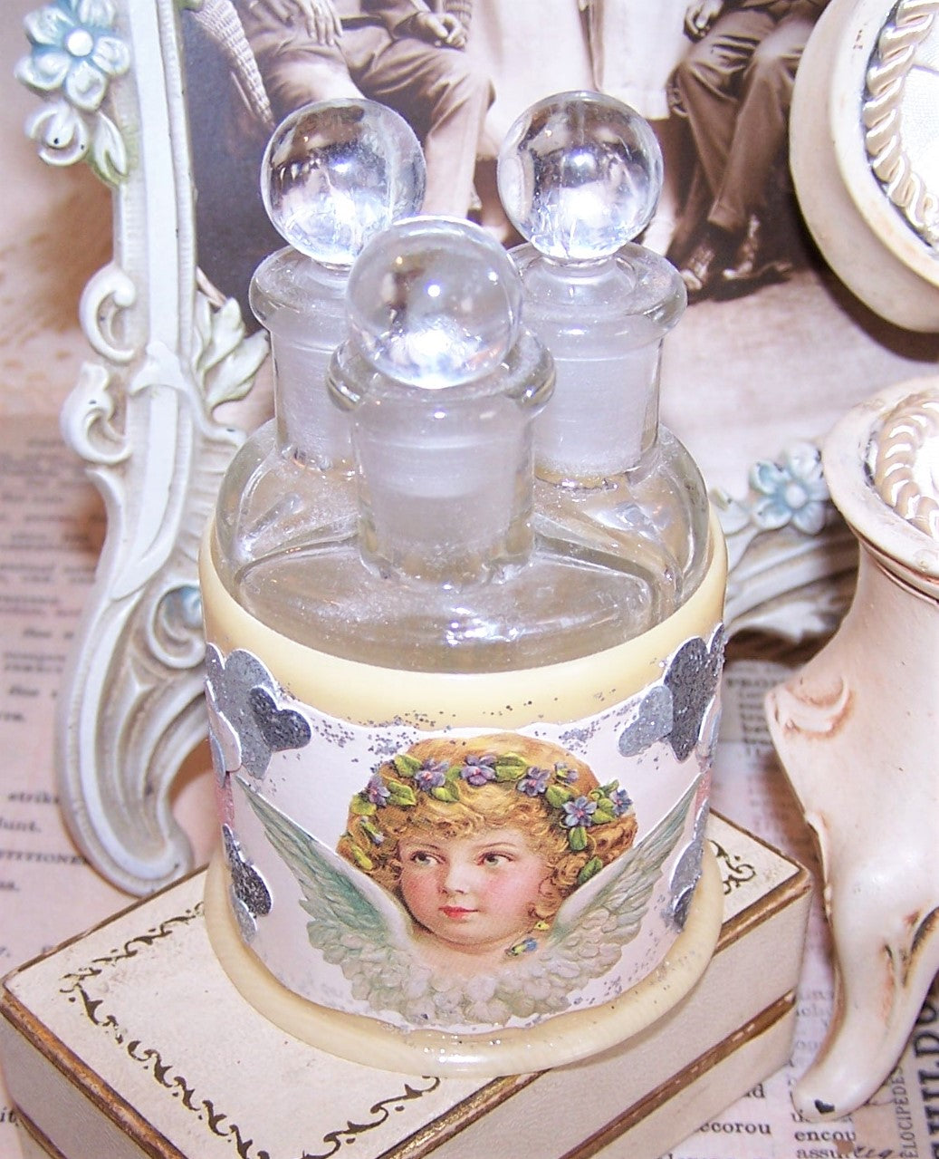 Upcycled Art Deco celluloid perfume / cologne holder with original glass bottles / stoppers. Angel graphics along with silver stars and pink rayon ribbon.
