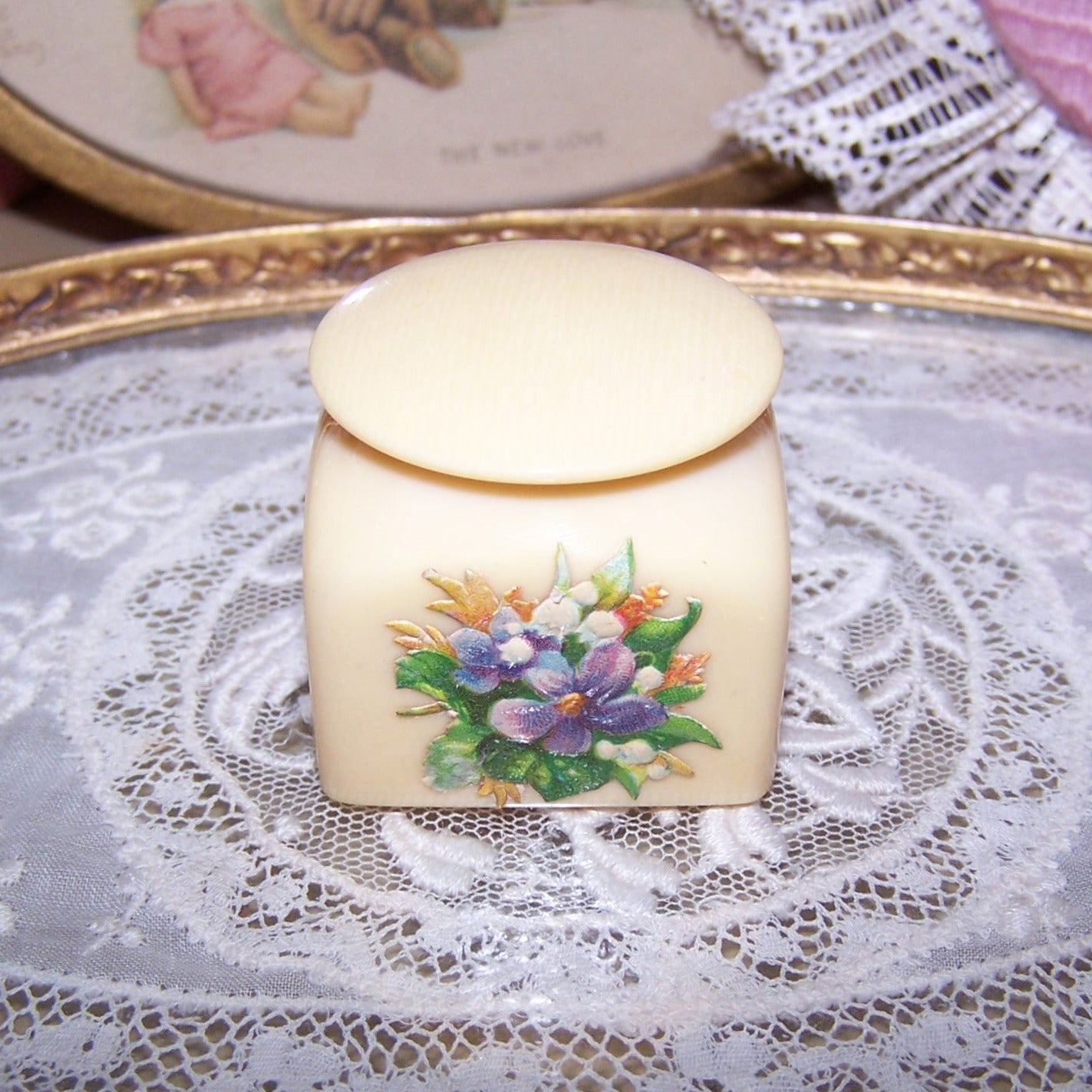 Art Deco celluloid powder container - mini trinket / jewelry box. Decorated with a Victorian die cut of flowers, height is 1-5/16". Nice display item for a doll!