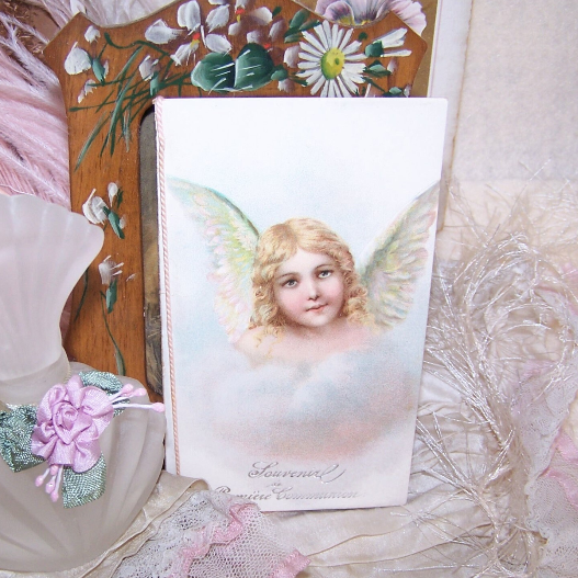 Made in France French Souvenir de Premiere Communion - Souvenir of First Communion that is in unused condition. The front cover depicts a lovely image of an angel while the inside displays a place for the name of the communiante and a lovely image of a Guardian Angel escorting a young girl on her walk. Size of the booklet i 4-3/4" x 3" approx. Condition is very nice BUT the pink cord has cut into the spine both at the top and the bottom - reinforcement in this area will need to be done.