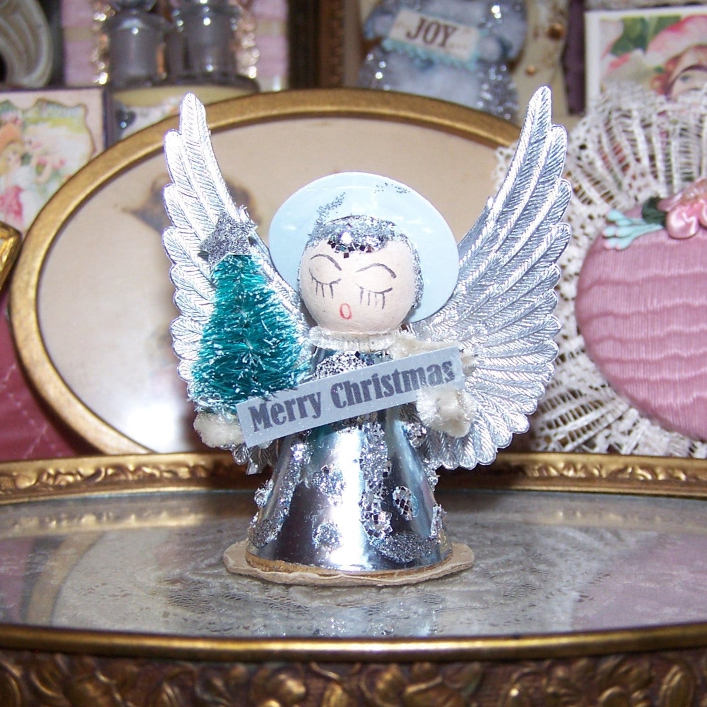 Upcycled 1960s Made in Japan foil, Dresden paper and glitter angel ornament. Ice blue and silver coloring. Stands 2-3/4" high; width is 2-1/4".