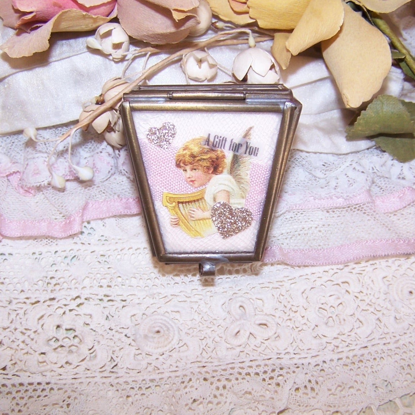 Repurposed brass trinket box with glass panels upcycled with pink cardstock, repro Victorian angel/flower die cuts, ribbons, cording and gold glitter stars.