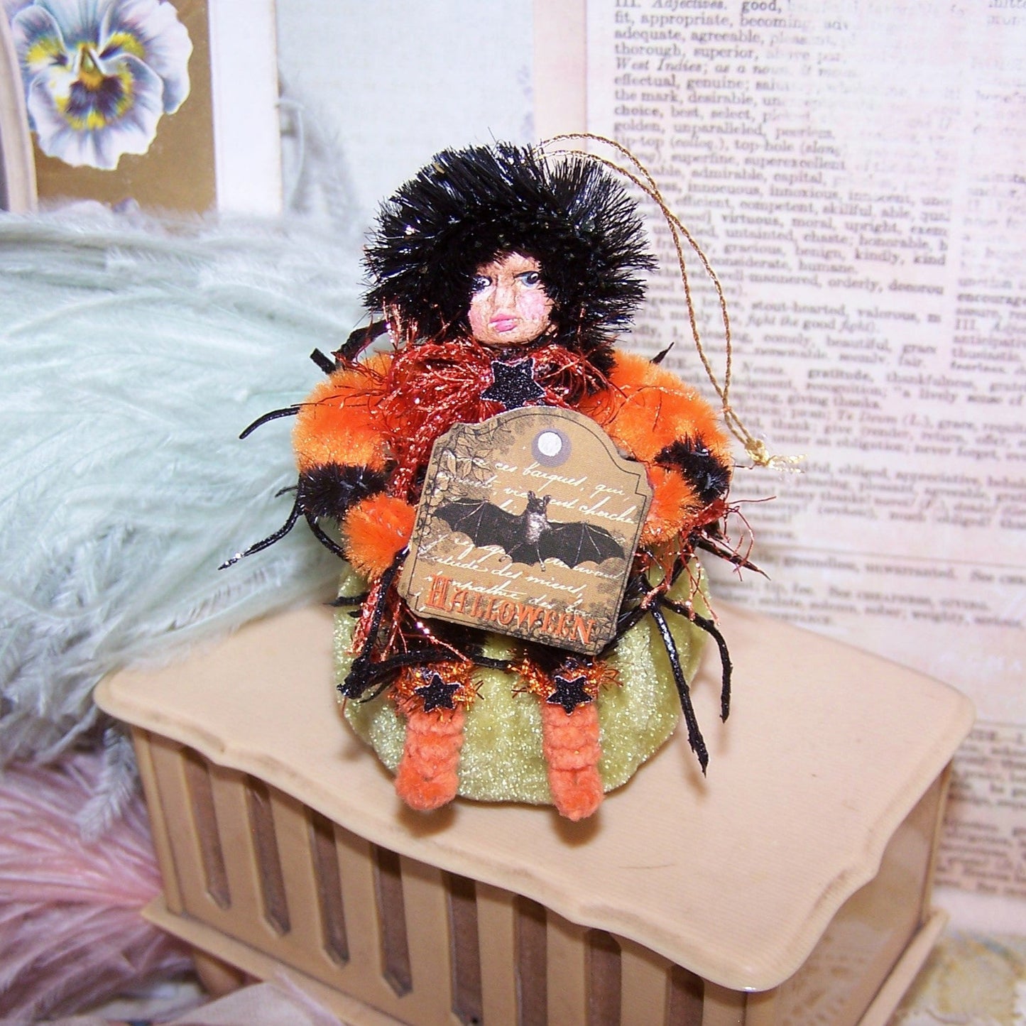 Mixed media OOAK Halloween ornament of a little girl carrying a Halloween sign while sitting on a velvet pumpkin. Handpainted face. 3-3/4" x 2-1/2"