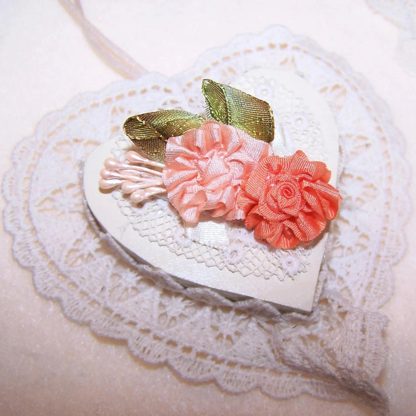 Handsewn ribbon applique of peach / orange silk flowers. Olive green leaves and sugar pips add to the look of the embellishment. Size is 1-7/8" x 1-1/8".