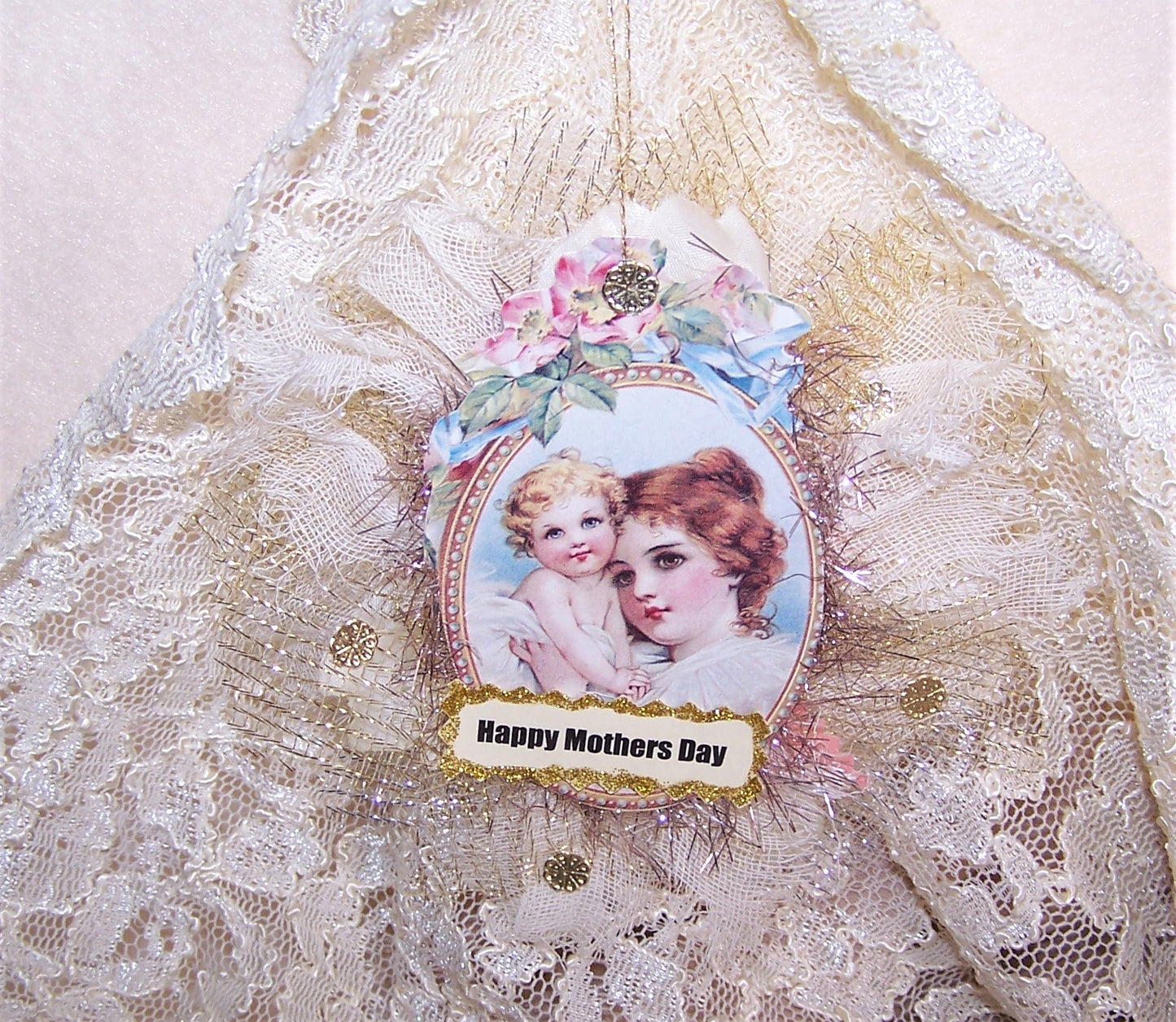 Victorian Revival Mother's Day ornament or decoration. A puffy fabric oval holds the image of a Mother and Child as well as cream fabric with gold highlights.