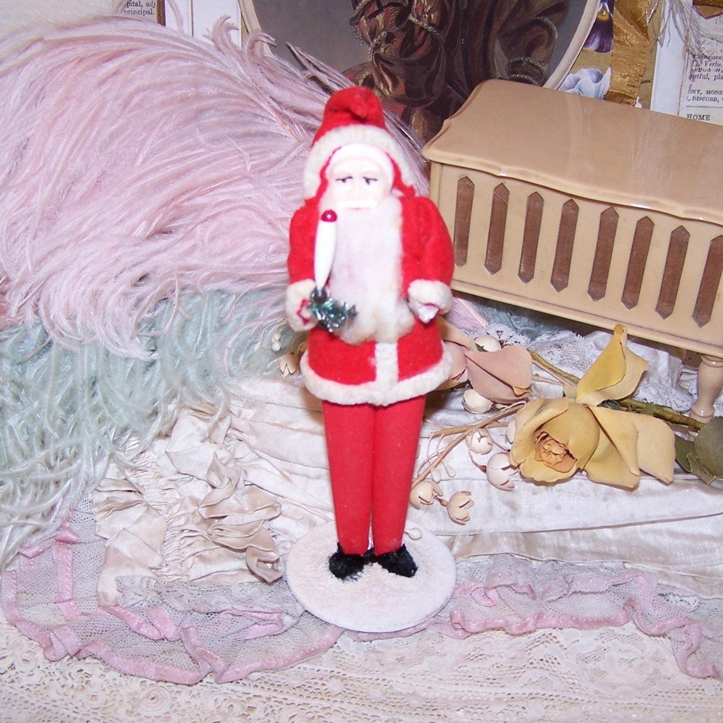 Vintage Made in Japan stand-up Santa Claus. Hard plastic face, the gent wears felt-like clothing with a chenille edge. He carries a candle and sprig of green.