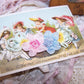 French Ribbonwork Revival applique for lingerie.  Pink & blue center blooms are shouldered by French Ombre yellow florals. Mint green silk loops act as leaves. 
