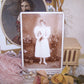 Antique Victorian cabinet card depicting a young girl graduate.  The lady not only wears flowers in her hair and on her dress, but she is surrounded by them. 