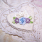 French Revival ribbonwork spray of 3 florals - a blue silk cabbage rose shouldered by a pair of mauve silk florettes, the centers set with freshwater pearls. 