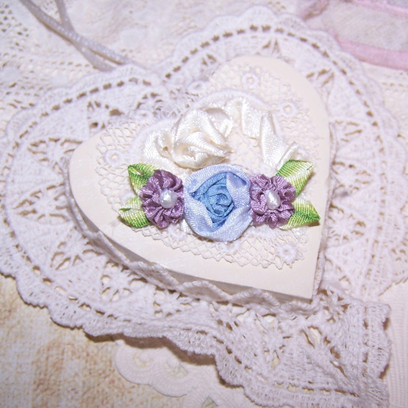 French Revival ribbonwork spray of 3 florals - a blue silk cabbage rose shouldered by a pair of mauve silk florettes, the centers set with freshwater pearls. 