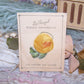 Art Deco La Royal Ribbon Ornament on Original Card - a mustard yellow flower with ruffled edge green leaves.  Very nice ribbonwork with a patina of age. 