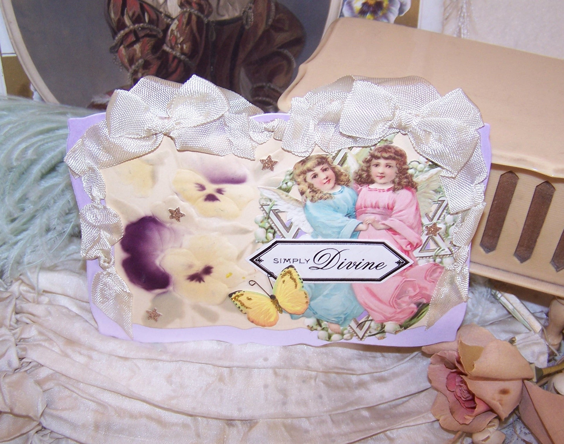 Handcrafted everyday greeting card/ornament of mixed materials.  Two Angels, Pansies and a Butterfly.  Sentiment is SIMPLY DIVINE.  Rayon Ribbon Hanger.