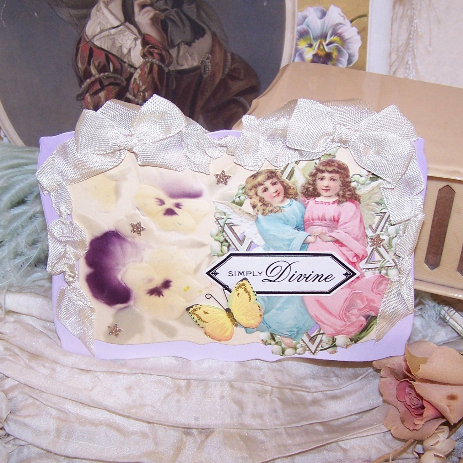 Handcrafted everyday greeting card/ornament of mixed materials.  Two Angels, Pansies and a Butterfly.  Sentiment is SIMPLY DIVINE.  Rayon Ribbon Hanger.