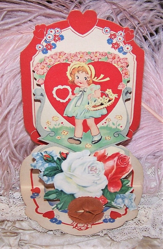 Dating to the 1920s or so and Made in the USA, here's a fold down, honeycomb Valentines Day card that has been used. With a sentiment to the front base as well as Aunt Minnie's signature, the bottom folds down to reveal a small red honeycomb as well as a pair of roses with additional flowers. The center design is that of a little girl carrying a basket of flowers and a lacy red heart. Condition is very fine with no tears, stains, breaks, etc. Just some light pencil marking to the back of the card. Size is 6