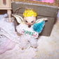 Decorative angel ornament with 'NOEL' on a lace surface