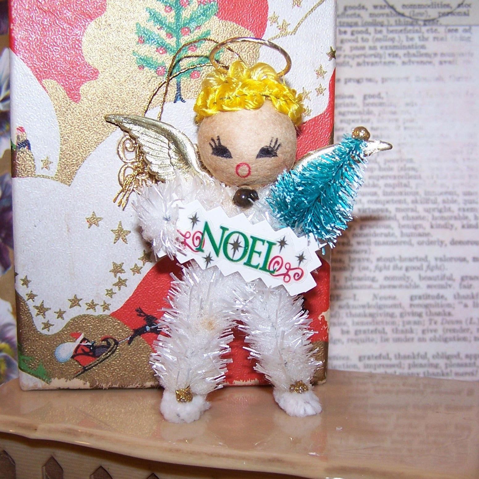Decorative angel figurine with 'NOEL' sign on a textured surface