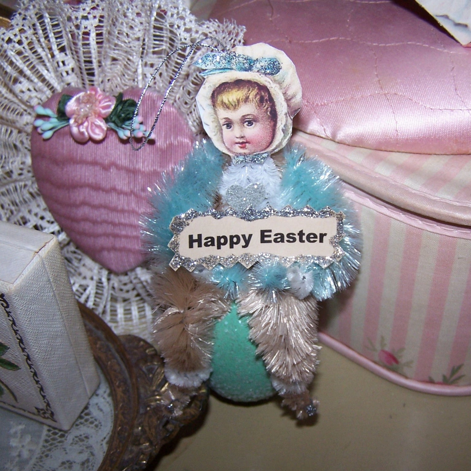 Handmade OOAK Victorian Revival chenille ornament. A little girl sits on a sparkly Aqua Egg and holds a sign that reads HAPPY EASTER! Ready for a basket!