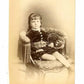 Antique Victorian cabinet card photograph depicting a young girl resting in a chair. The child appears to be dressed in a velvet outfit with tartan sash. 