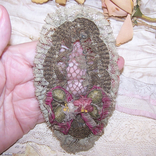 Art Deco French ribbonwork piece from the top of a ladies brush.  Gilt metallic lace, blue/grey cotton lace and French Ribbonwork florals.  5" x 2-3/4". 