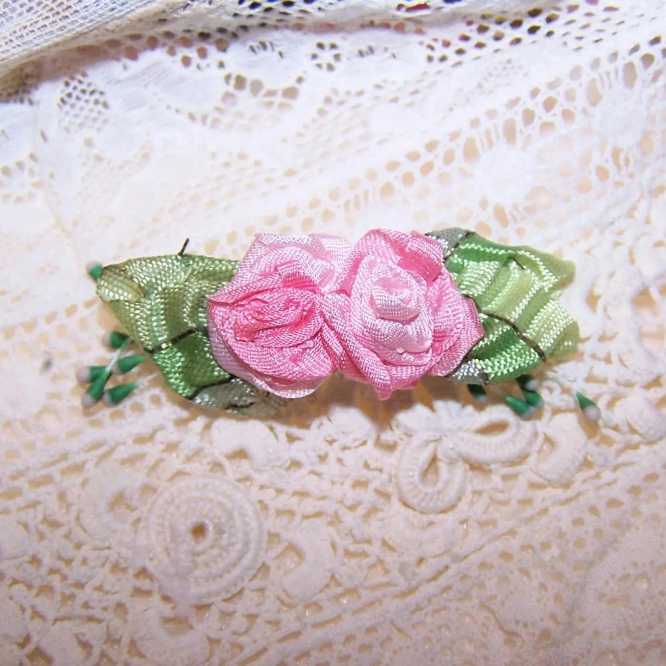 Antique French ribbonwork - a pair of pink ribbon flowers with green French striped ombre ribbon leaves. Further decoration of sugar pips.  1-3/4" x 9/16".