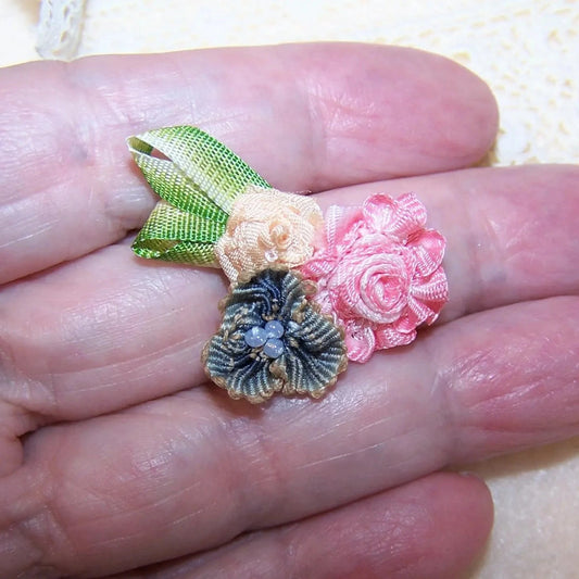 Antique French ribbonwork applique composed of 3 florals - pink ombre, blue ombre and yellow.  Lime green leaves. 1-3/8" x 7/8".  Entirely hand sewn.  