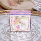 French C.1920 lidded jewelry box with image of a young girl standing against a wall covered in flowers. The box measures 1-5/8" square; depth is 5/8".