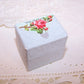 Light blue paper ring box with slotted insert on the inside and Antique Victorian die cut reading WITH MY LOVE to the top. 1-1/4" x 15/16" x 1-3/16" high. 