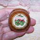 Paper jewelry box with Christmas tag of holly and a sentiment of CHRISTMAS GREETINGS.  Pink cotton on the inside. Size is 1-1/2" wide x 11/16" high. OOAK!