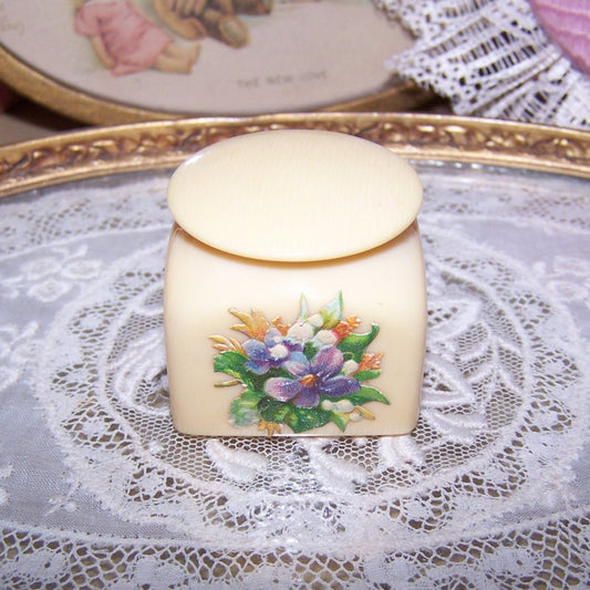 Art Deco celluloid powder container - mini trinket / jewelry box. Decorated with a Victorian die cut of flowers, height is 1-5/16". Nice display item for a doll!