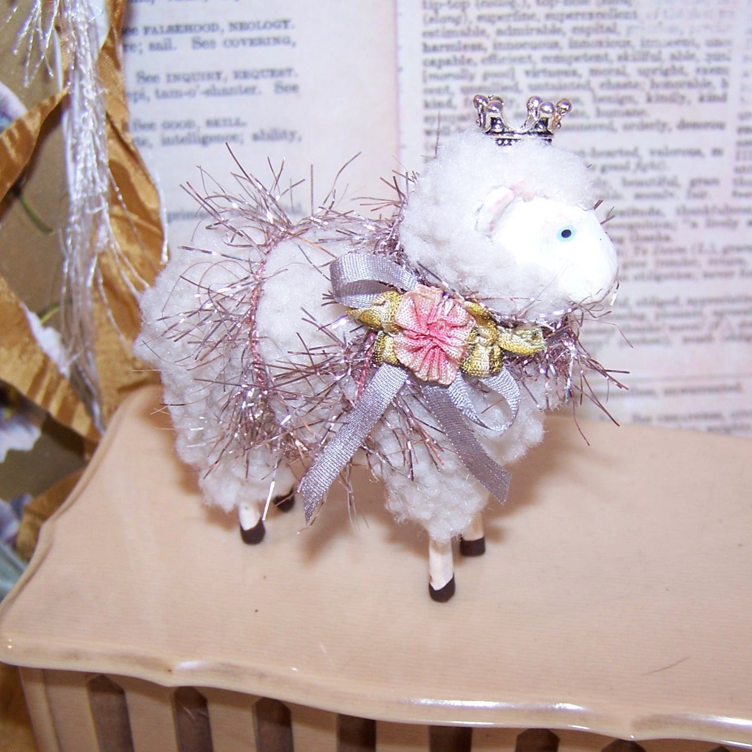 A sheep - lamb - ewe for either the Easter or Christmas season. The animal is decorated in pink tinsel, pink silk ribbon, a ribbonwork rose and a silver crown.