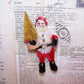 Handcrafted chenille ornament of Santa Claus.  In a retro inspired design, Santa carries a gold glitter Christmas tree.  Gold Cord for hanging from a tree. 