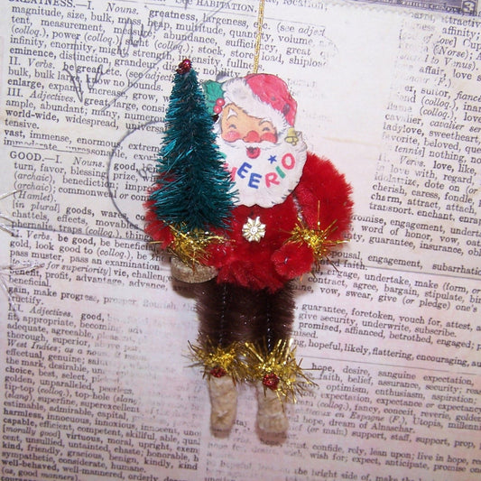 OOAK Santa Claus Christmas ornament. Made of chenille, Santa sports a 1950s Christmas sticker face (reads CHEERIO) and Christmas tree. 4" x 2"