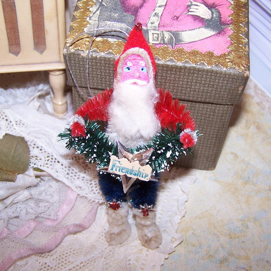 Red, White & Blue chenille Christmas ornament of Santa Claus.  Retro inspired, Santa is very patriotic & carries a bottlebrush garland; sentiment is Friendship!