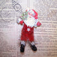 Limited Edition Santa Claus Christmas ornament. Made of chenille, Santa sports a 1950s Christmas sticker face and holds a Christmas tree. 4" x 2" approx.