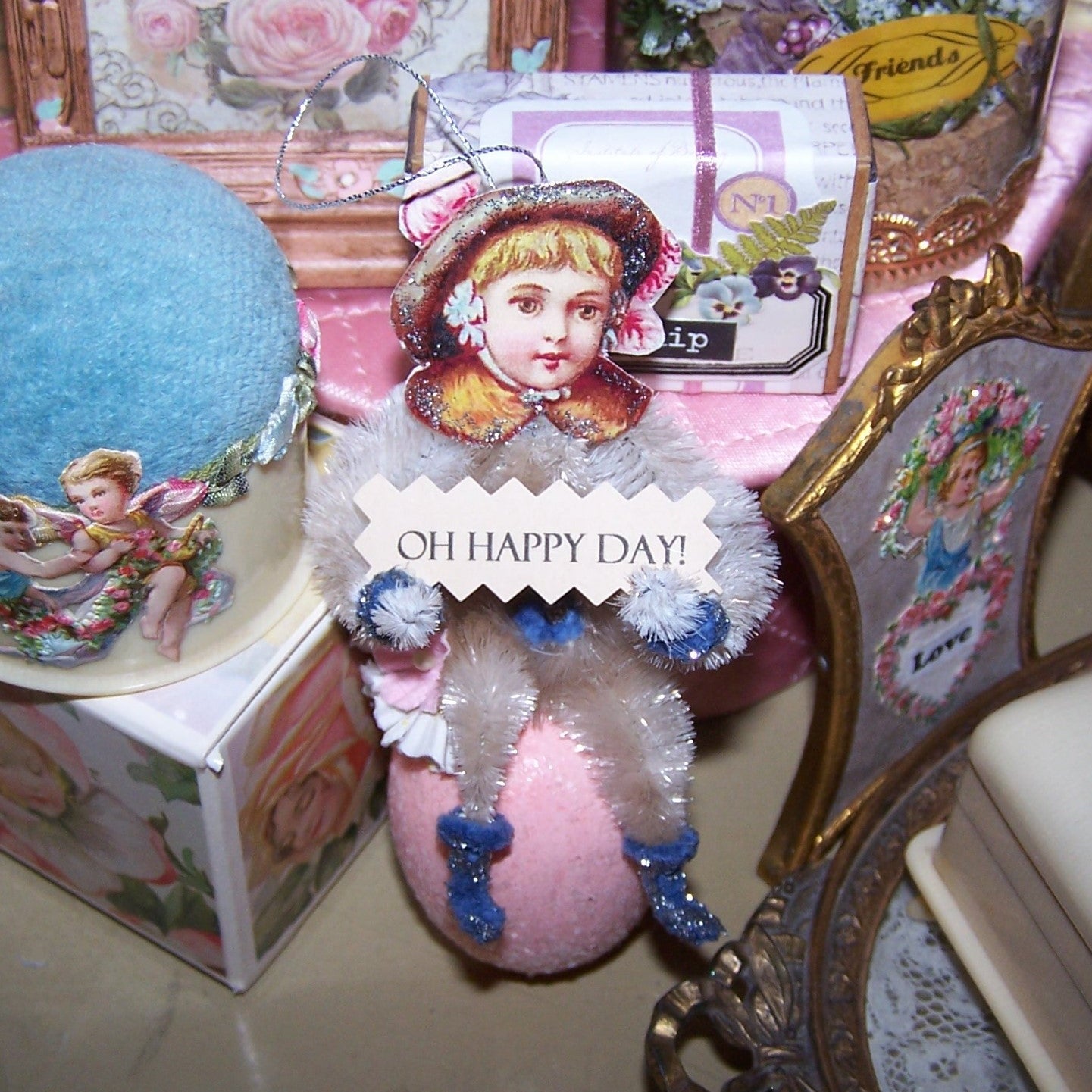 Handmade Victorian Revival Spring chenille ornament. A little girl sits on a sparkly Pink Egg and holds a sign that reads OH HAPPY DAY. All occasion gift idea!