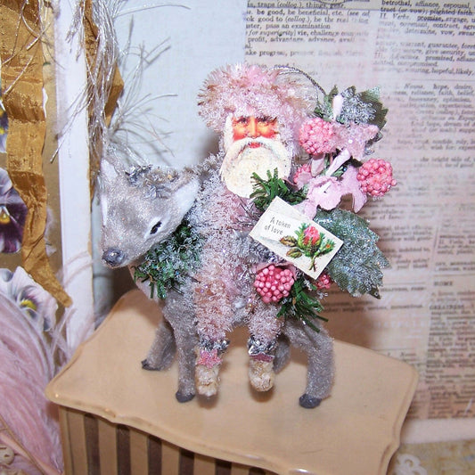 Original mixed media holiday ornament. My pink chenille Santa sits on a grey fawn and holds berries and a sign that reads A TOKEN OF LOVE.  4-3/4" x 3-1/2"