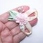Handsewn ribbon applique of a single pink rose, mint green leaves and cream loopy swirls. Mint green/baby pink sugar pips add a touch more color. 2-1/4" x 2" 