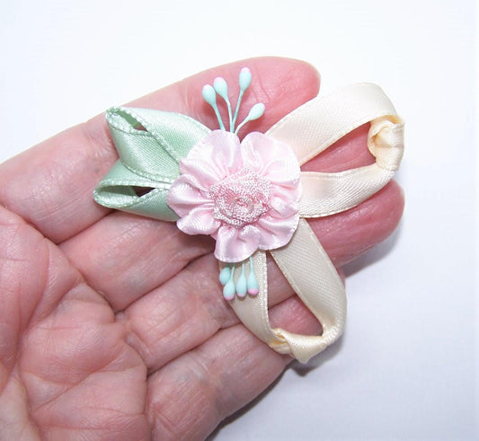 Handsewn ribbon applique of a single pink rose, mint green leaves and cream loopy swirls. Mint green/baby pink sugar pips add a touch more color. 2-1/4" x 2" 