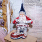 Handcrafted One of a Kind chenille & clay face Santa Claus sitting on a "sequin and pin" boot. He holds a sign reading RED WHITE & BLUE Forever.  6" x 2-1/2" 