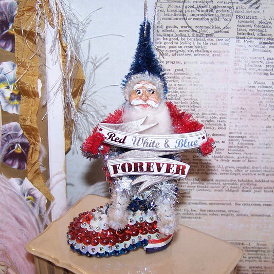Handcrafted One of a Kind chenille & clay face Santa Claus sitting on a "sequin and pin" boot. He holds a sign reading RED WHITE & BLUE Forever.  6" x 2-1/2" 