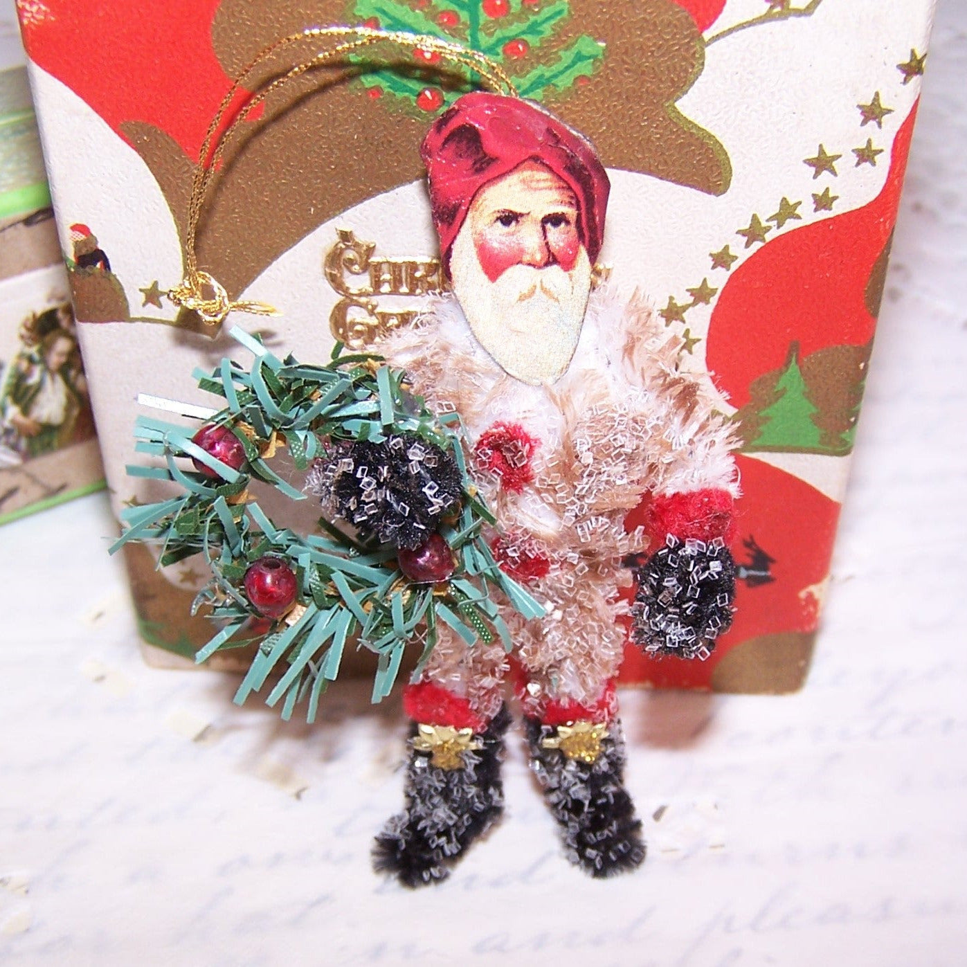 Retro Look glittered chenille Santa Claus Christmas ornament.  Repro Victorian die cut face, Dresden paper accents & a bottlebrush wreath complete the design.  