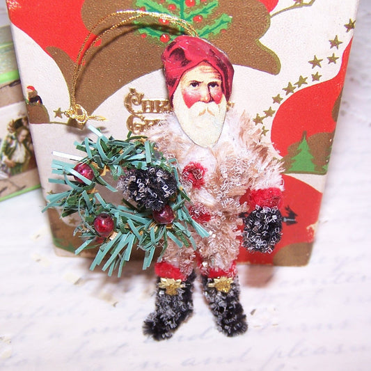 Retro Look glittered chenille Santa Claus Christmas ornament.  Repro Victorian die cut face, Dresden paper accents & a bottlebrush wreath complete the design.  