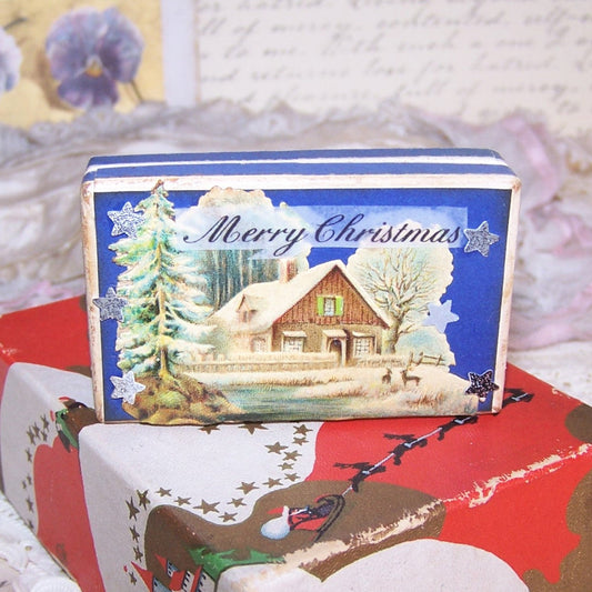 Vintage pharmacy pill box with a Christmas theme. Top design is an Antique Victorian die cut of a log cabin winter scene; sentiment is MERRY CHRISTMAS. 